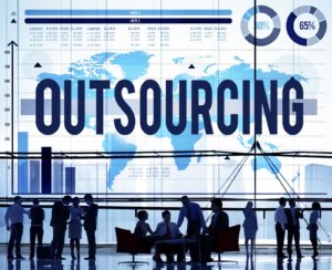 Large group of people in a business lobby in front of a giant map of the world with outsourcing as a large label.